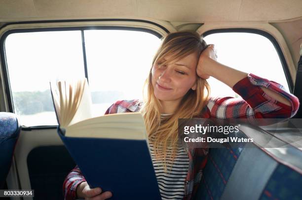 woman reading book in car. - passagerarsäte bildbanksfoton och bilder