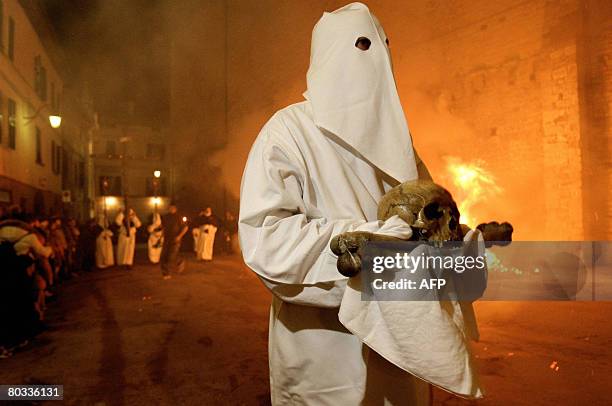 An Italian Christian in long hooded robe carries a cross during the Good Friday procession through the streets of Gubbio, Umbria, on March 21, 2008....