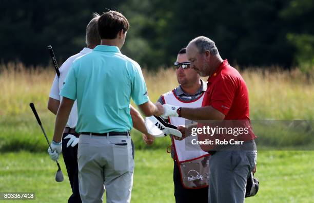 Boo Weekley of the United States bumps fists with Ollie Schniederjans of the United States and Trey Mullinax of the United States after withdrawing...