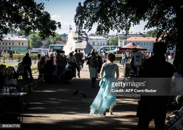 Woman wearing an evening dress walks among tourists next to the statue of Peter the Great in Saint Petersburg on June 28, 2017. / AFP PHOTO / Mladen...