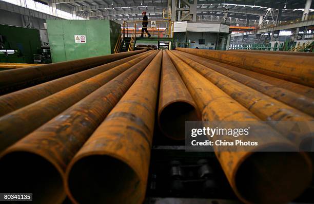 Worker walks past seamless casing pipes at a pipe rolling plant of the Tianjin Pipe Group Corp, the largest seamless casing maker in China, on March...