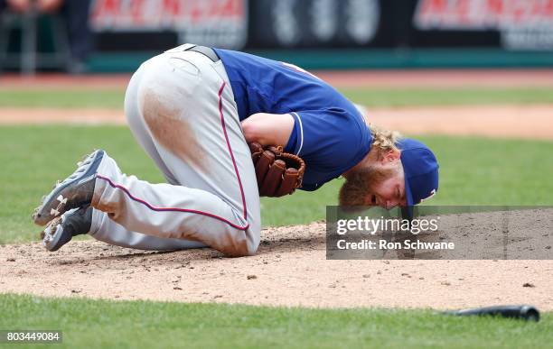 Starting pitcher Andrew Cashner of the Texas Rangers falls to the ground after being hit by a broken bat from Edwin Encarnacion of the Cleveland...