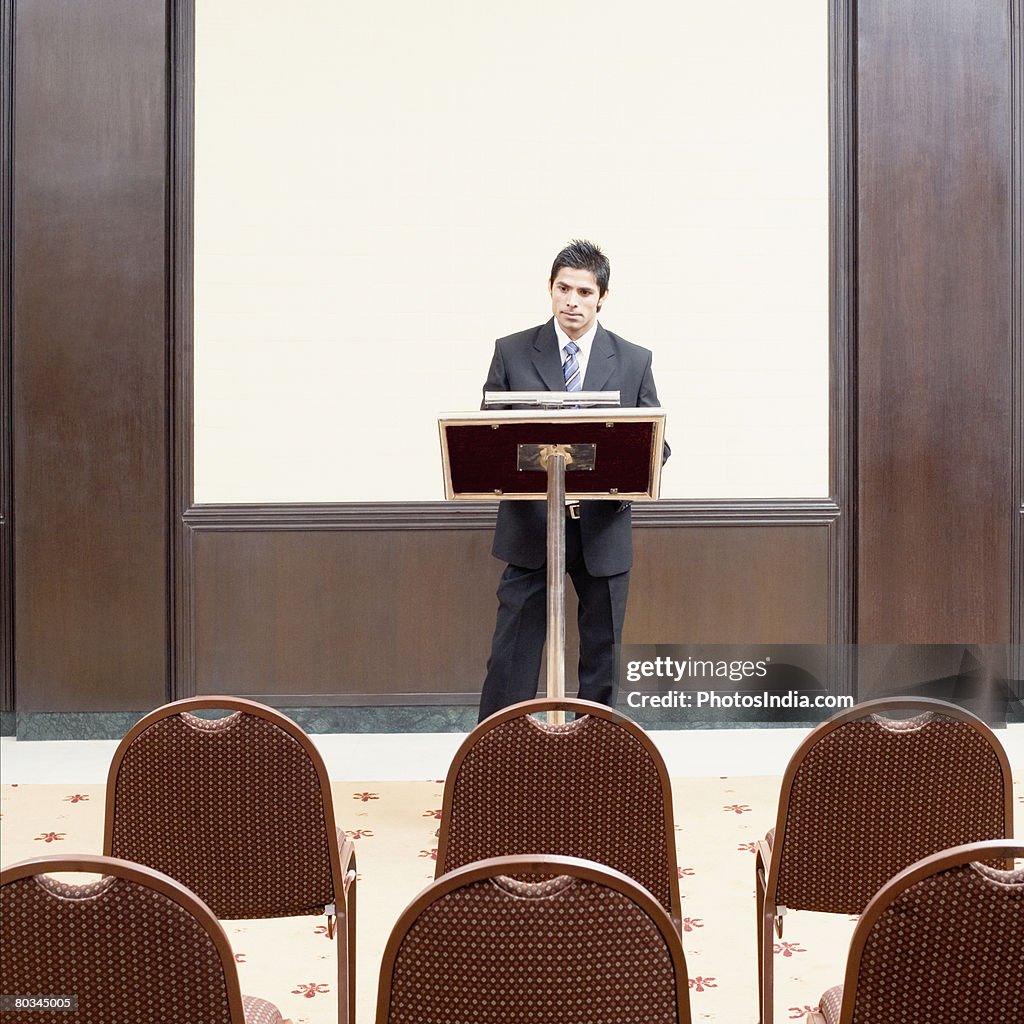 Businessman standing at a lectern in a conference room