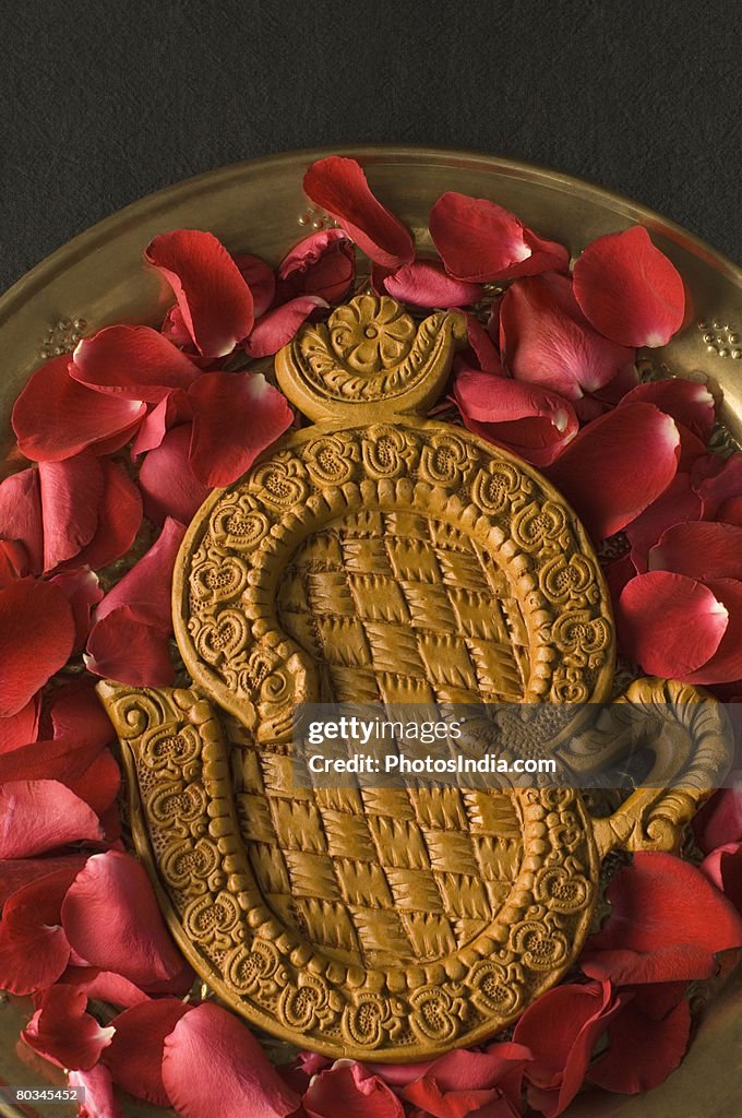 Close-up of a ohm symbol with rose petals in a plate