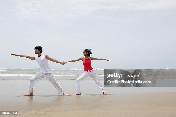 young couple exercising on the beach - yoga goa woman stock pictures, royalty-free photos & images