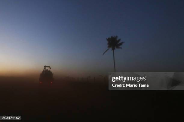 Farm tractor is towed on a truck kicking up Amazon soil as it travels in a deforested section of the Amazon rainforest on June 28, 2017 near...