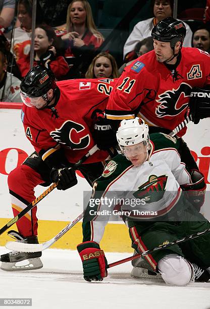 Kim Johnsson of the Minnesota Wild is knocked down by Owen Nolan and Craig Conroy of the Calgary Flames at Pengrowth Saddledome March 22, 2008 in...