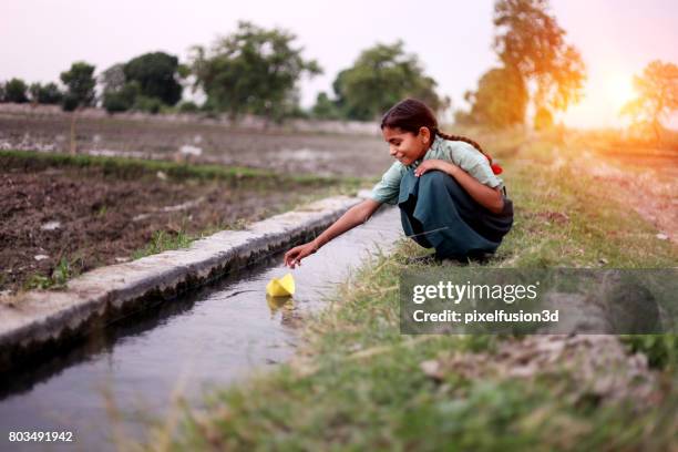 kleines mädchen fließenden papier boot im wasser - children india stock-fotos und bilder