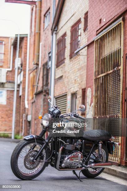 moto clásica de estilo retro en un callejón - triumph motorcycle fotografías e imágenes de stock