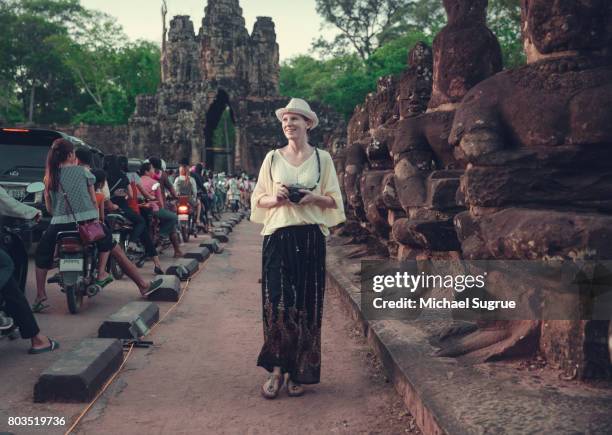 female tourist walks among statues at sunset near bayon temple, near angkor wat, siem reap, cambodia. - black blouse stock pictures, royalty-free photos & images