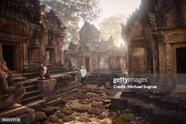 a female tourist photographs banteay srei temple at sunrise, near angkor wat, siem reap, cambodia. - angkor wat stock pictures, royalty-free photos & images