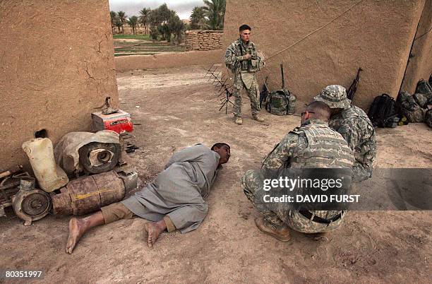 Soldier from Ghostrider Company 3rd Squadron 2nd Stryker Cavalry Regiment questions a detained Iraqi man with alleged links to Sunni insurgent groups...