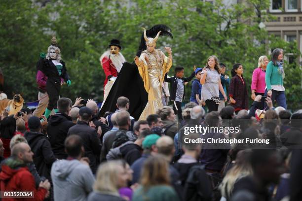 People parade on a 100m long catwalk installed high above the ground as part of What Is The City But The People? show in Piccadilly Gardens on June...