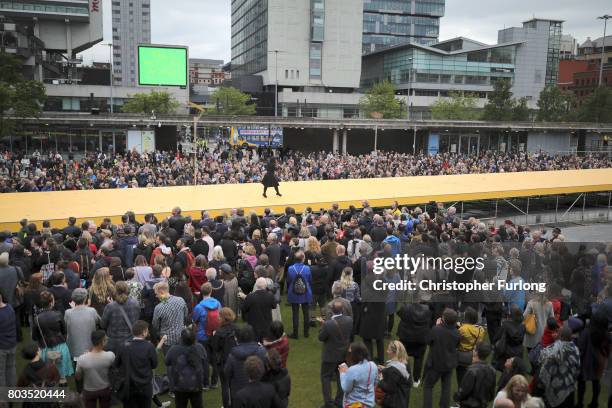 People parade on a 100m long catwalk installed high above the ground as part of What Is The City But The People? show in Piccadilly Gardens on June...