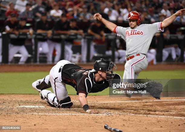 Chris Herrmann of the Arizona Diamondbacks stretches to catch a throw while keeping his toe on home plate to get a force out as Daniel Nava of the...