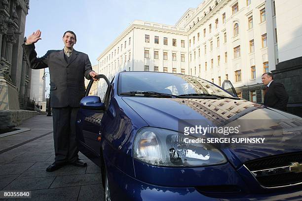 Ukrainian Leonid Stadnik 2.59 meter tall, the world's tallest living man, waves as he poses for the media by the Chevrolet Tacuma car presented to...