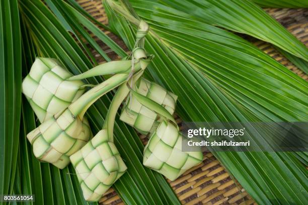 ketupat, kupat or tipat is a type of dumpling made from rice packed inside a diamond-shaped container of woven palm leaf pouch. it is commonly found in indonesia, malaysia, brunei and singapore. - ketupat stock pictures, royalty-free photos & images