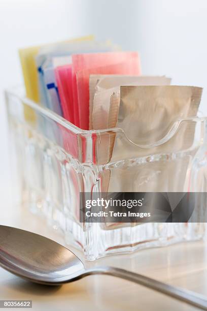 sugar and sweetener packets next to spoon - artificial sweetener stock pictures, royalty-free photos & images