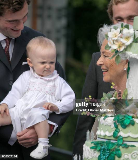 Queen Paola of Belgium looks at Prince Amedeo of Belgium, Archduke of Austria-Este and his baby daughter Anna-Astrid van Oostenrijk-Este in front of...