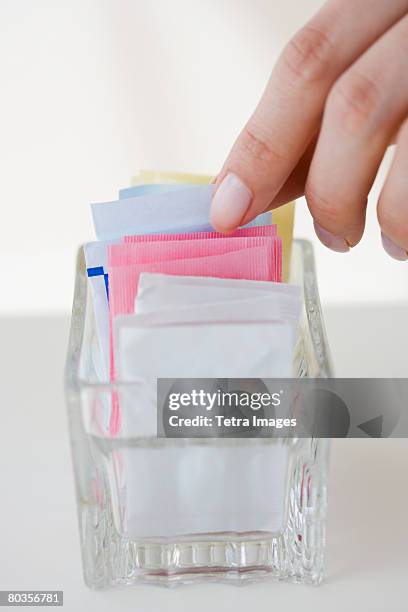 woman reaching for sweetener packet - artificial sweetener stock pictures, royalty-free photos & images