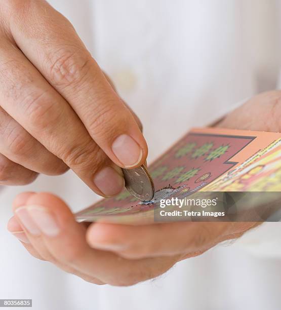 man scratching lottery card with coin - kansspel stockfoto's en -beelden