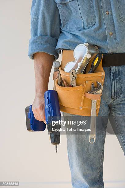 man wearing tool belt and holding drill - middle stock pictures, royalty-free photos & images