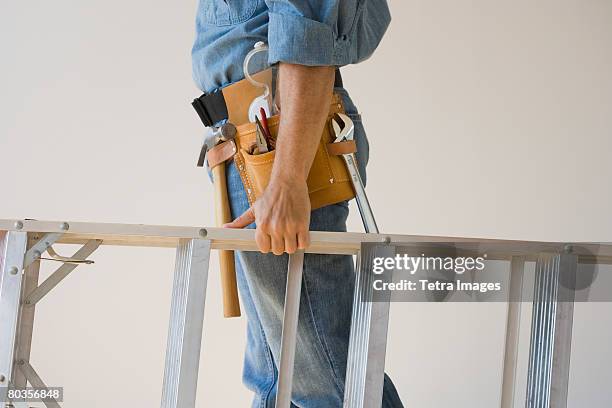 man wearing tool belt and holding ladder - tool belt stock pictures, royalty-free photos & images