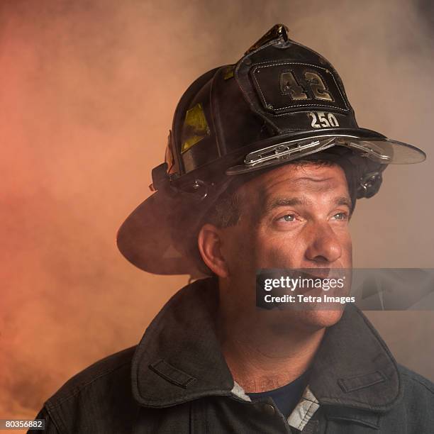 male firefighter in smoke - firefighters helmet stock pictures, royalty-free photos & images