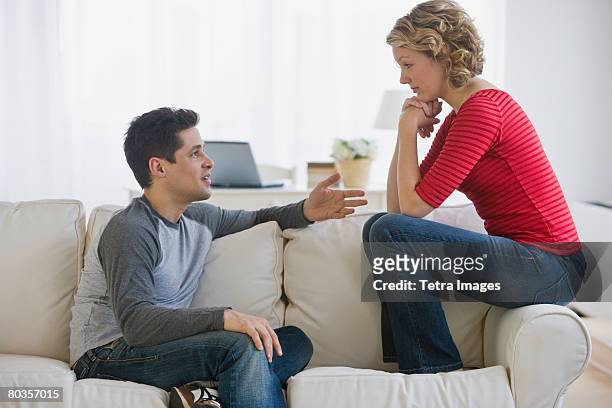 couple talking on sofa - males arguing stock pictures, royalty-free photos & images