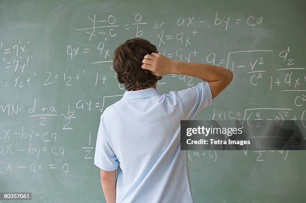 teenaged boy looking at math equations on blackboard - back of heads stock pictures, royalty-free photos & images