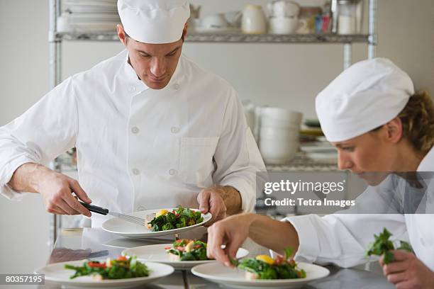 male and female chefs plating food - food plating fotografías e imágenes de stock