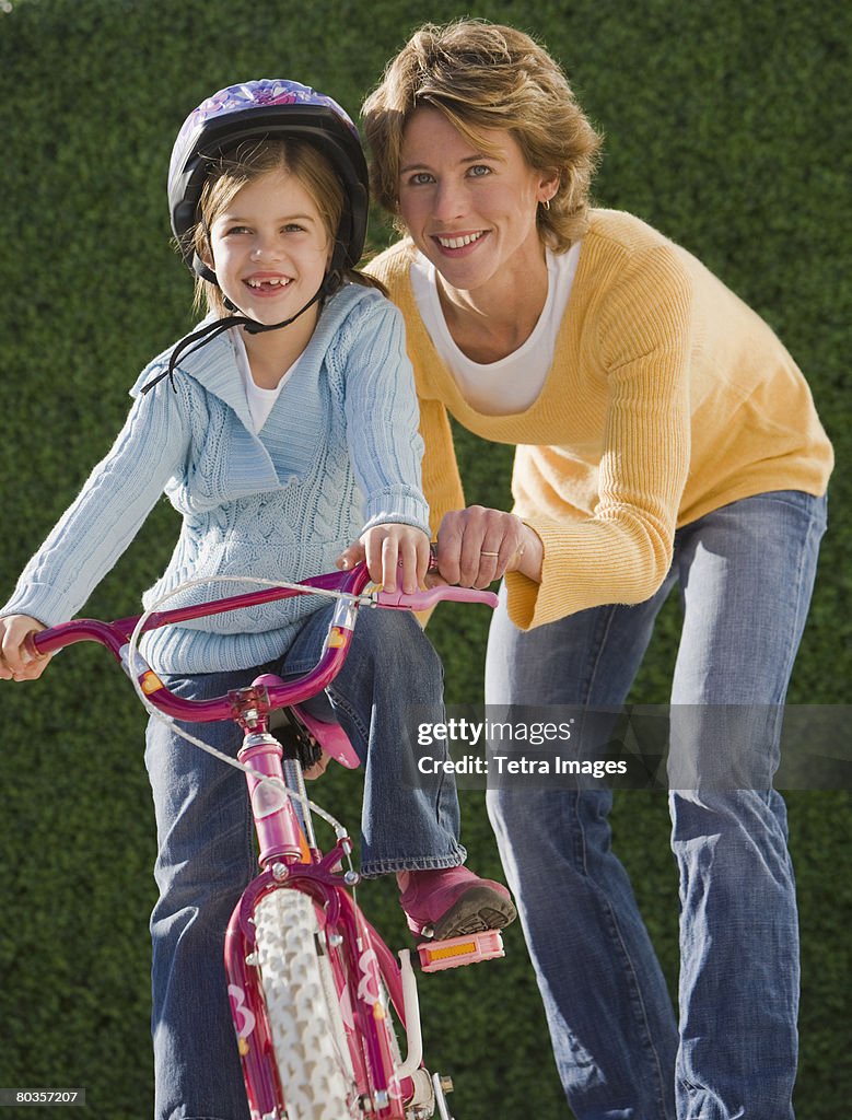 Mother helping daughter ride bicycle