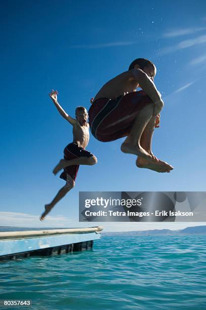 brothers jumping off dock into lake, utah, united states - vertical jump stock pictures, royalty-free photos & images