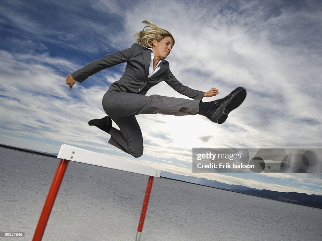 Businesswoman jumping over hurdle, Salt Flats, Utah, United States