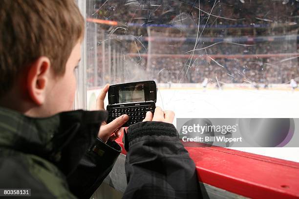 Young fan of the Buffalo Sabres sits along the glass texting on his cell phone while watching the game against the Tampa Bay Lightning on March 19,...