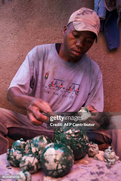 This photograph taken on May 11 shows a malachite worker applying paint on malachite stones at a malachite wokshop in Lubumbashi, DR Congo. There is...