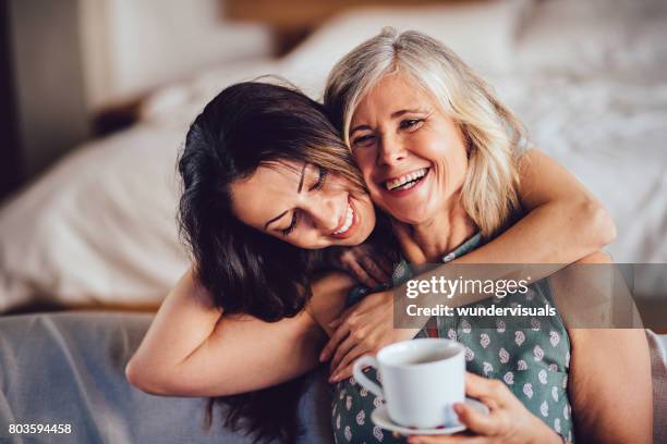 fille adulte embrassant gai senior mère aimante à la maison - women drinking coffee photos et images de collection