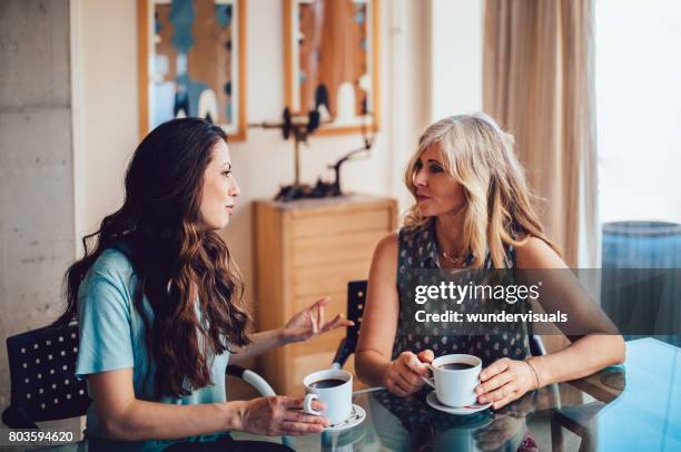 senior mother and daughter drinking coffee together at home - mother adult daughter stock pictures, royalty-free photos & images