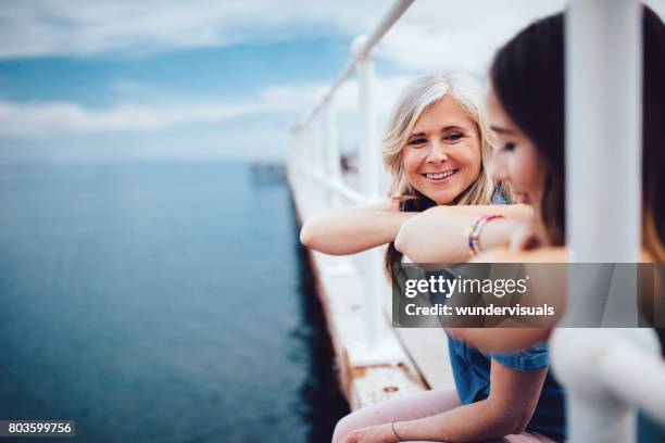 senior mother and teenage daughter relaxing together on a pier - eurasian female stock pictures, royalty-free photos & images