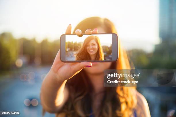 hermosa mujer hace retrato del uno mismo en vista del smartphone de pantalla - hacer foto fotografías e imágenes de stock