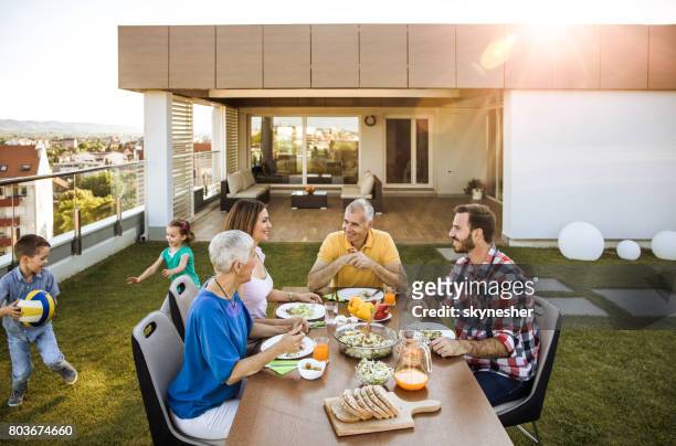 happy multi-generation family enjoying during a meal on the balcony. - penthouse girl stock pictures, royalty-free photos & images