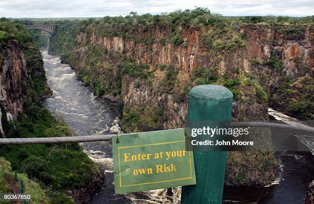 Sign warns tourists from proceeding from a lookout point over the Zambezi River March 17, 2008 below Victoria Falls, Zimbabwe. Called one of the...