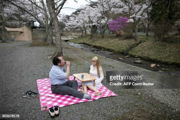 In this picture taken on April 21 62-year-old Senji Nakajima picnics with his silicone sex doll Saori under cherry blossoms in Yamanashi prefecture....