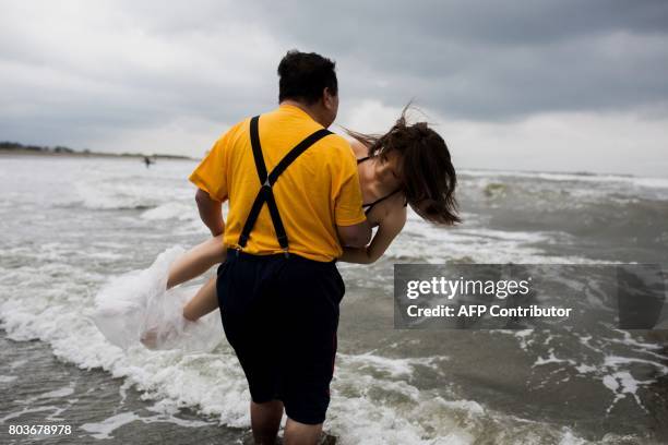 In this picture taken on June 14 62-year-old Senji Nakajima carries his silicone sex doll Saori into the water to surf at Kujukuri beach, Chiba...