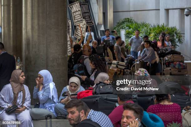 Activists demonstrate as international travelers arrive on the first day of the the partial reinstatement of the Trump travel ban, temporarily...