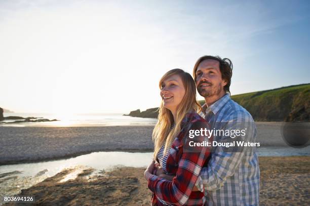 couple embracing at beach and smiling. - looking backwards stock pictures, royalty-free photos & images