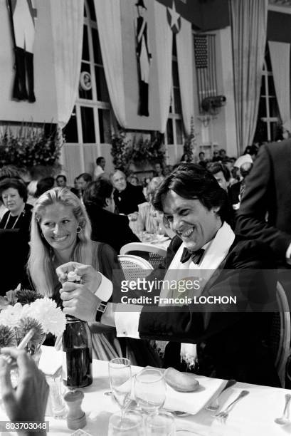 Alain Delon ouvrant une bouteille de champagne lors d'un dîner au Festival de Deauville en septembre 1976, en France.