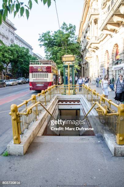 entrance of the budapest metro station from the street with people passing on sidewalk and bus in the street - budapest metro stock pictures, royalty-free photos & images