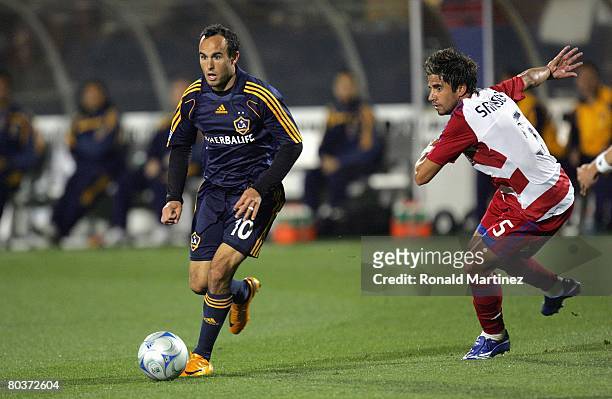 Midfielder Landon Donovan of the Los Angeles Galaxy moves the ball past Marcelo Saragosa of FC Dallas during a charity preseason match on March 15,...