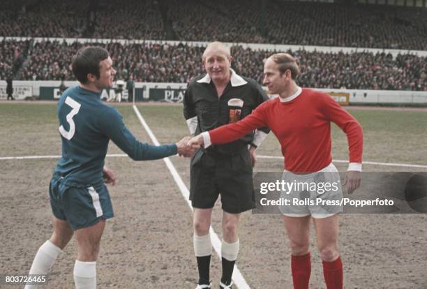 English professional footballers Bobby Charlton of Manchester United and Ron Harris of Chelsea shake hands in front of the referee at the centre spot...